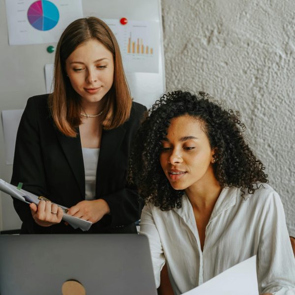 Two confident women working together on a project in a modern office.